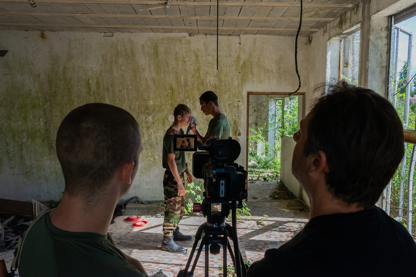 Tournage dans une pièce abandonnée, deux comédiens en treillis devant la caméra