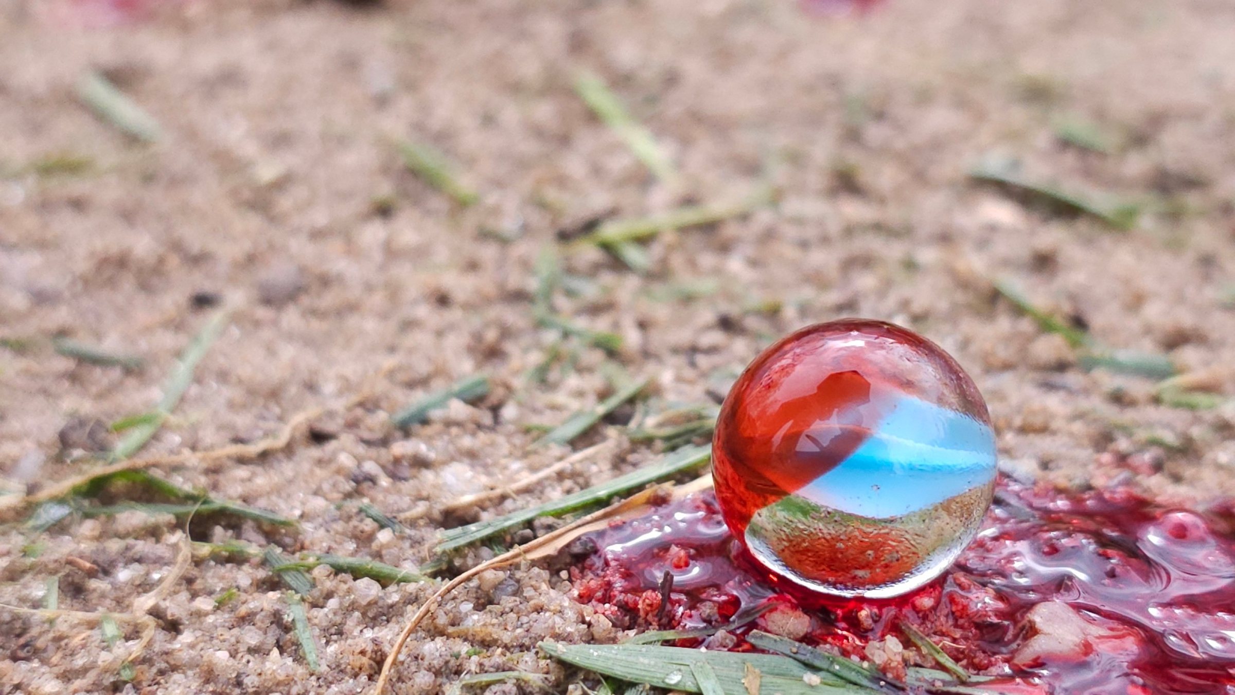 Vestiges : une bille de verre posée dans une flaque de sang sur le sable